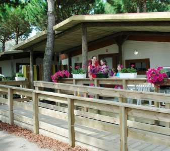 Terrazza con fiori in vaso e ringhiera in legno. Due persone in piedi.