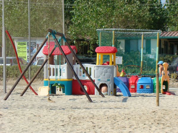 Un parco giochi colorato su una spiaggia con altalene e scivoli.