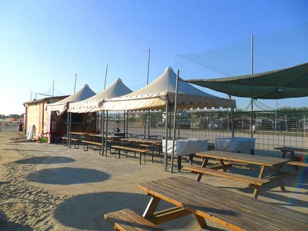 Tavoli e tende su una spiaggia vuota.