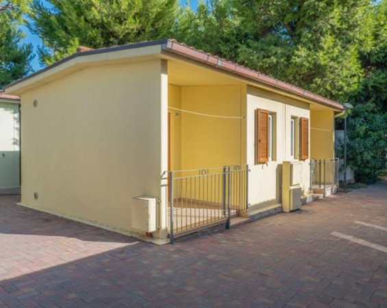 Una casetta gialla con finestre marroni e tetto rosso.