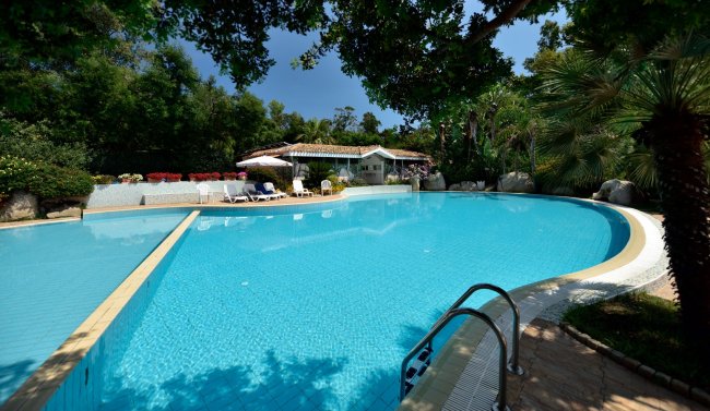 Ampia piscina con casa bianca sullo sfondo.