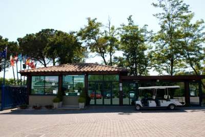 Struttura con tetto in tegole e golf cart bianco parcheggiato, con alberi sullo sfondo.
