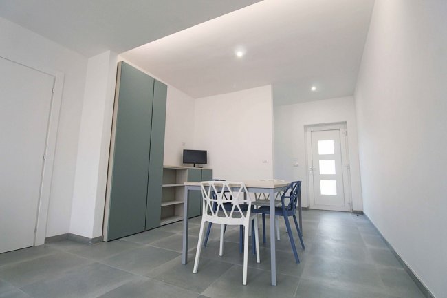 Soggiorno con tavolo bianco e sedie colorate.