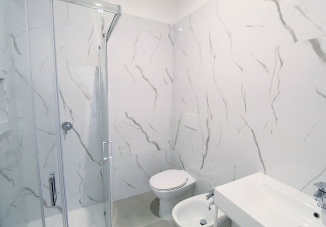 Bagno con doccia e pareti effetto marmo.
