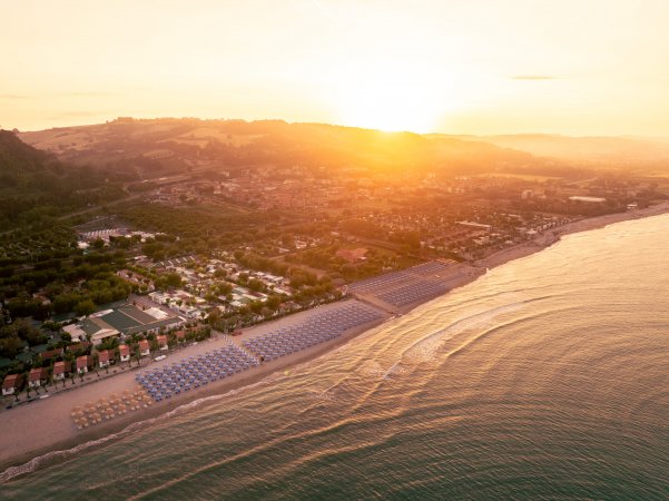 Spiaggia con file di ombrelloni al tramonto.