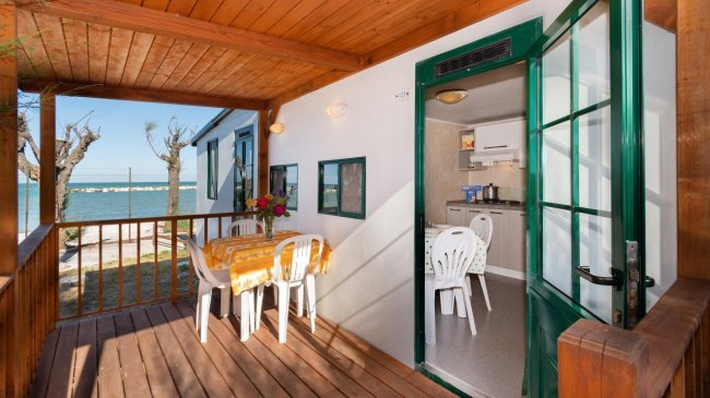 Veranda in legno con vista mare e tavolo per quattro.