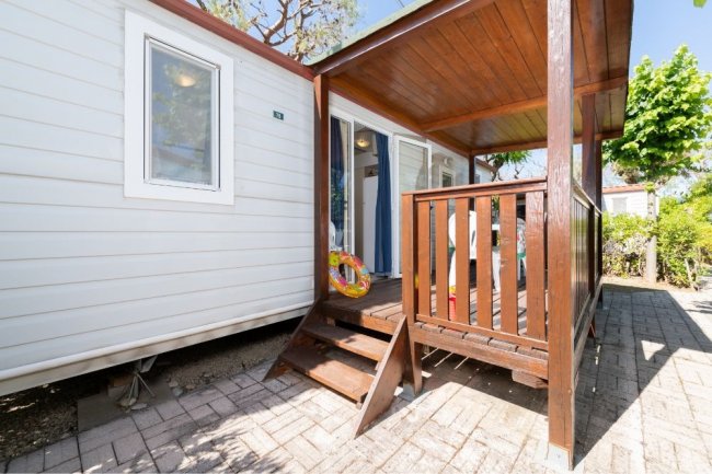 Veranda con scala, pareti bianche, ingresso aperto.