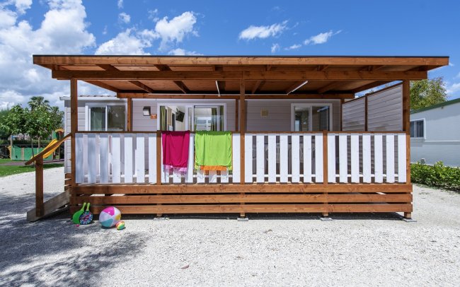 Casetta in legno con teli colorati e palla.