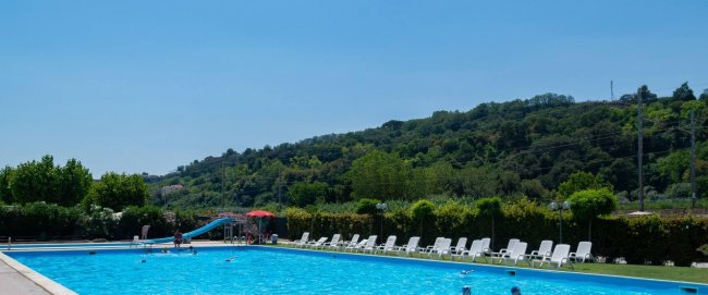 Piscina esterna con lettini e colline sullo sfondo.