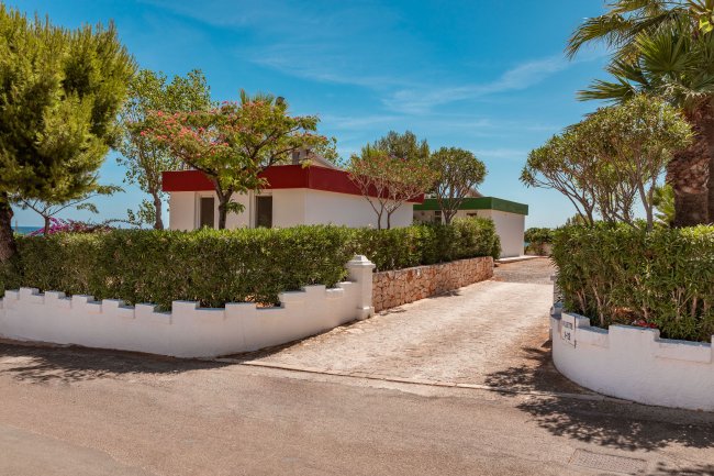 Piccolo edificio con giardino e vialetto, cielo sereno.