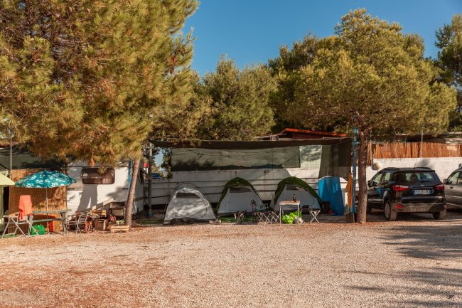 Campeggio con tende e roulotte tra gli alberi.