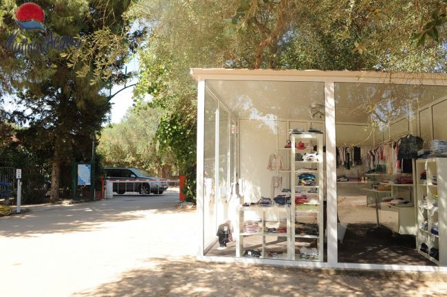 Edificio moderno con vetrine trasparenti e abbigliamento esposto, circondato da alberi.