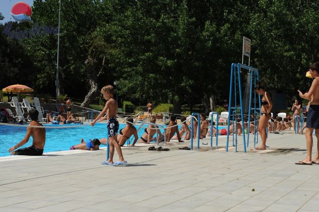 Persone a bordo piscina in un'area esterna con verde circostante.