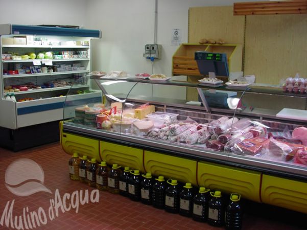 Banchi refrigerati con carne e formaggi in un negozio.