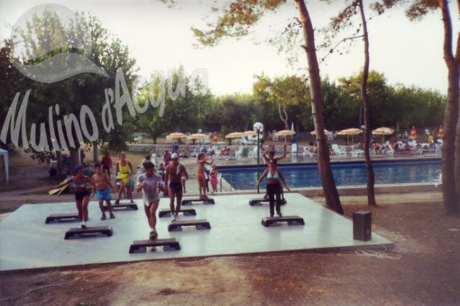 Persone fanno aerobica su una piattaforma vicino a una piscina.