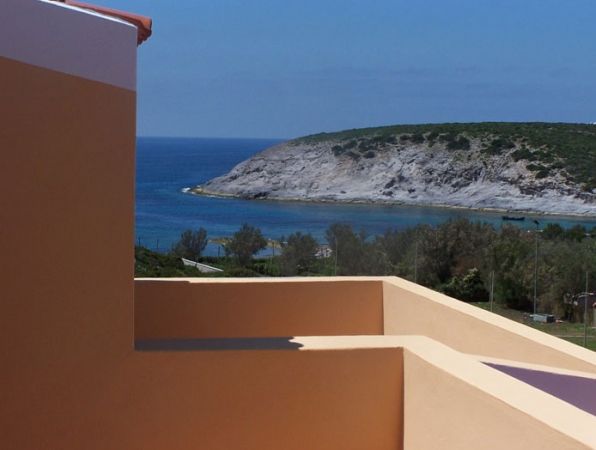 Un balcone con vista sul mare e una collina rocciosa.