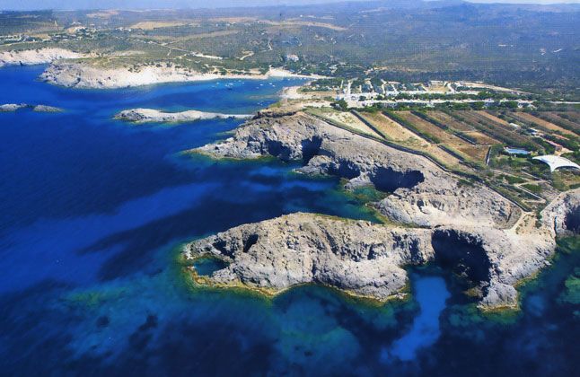 Vista aerea di scogliere rocciose e mare blu intenso.