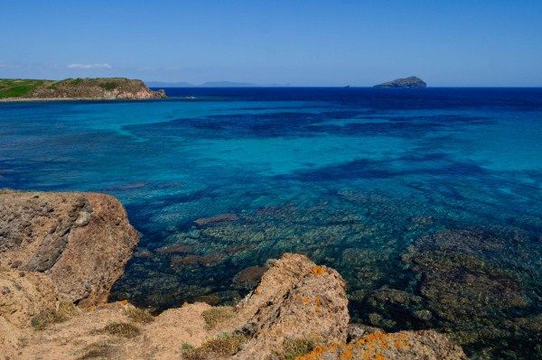 Scogliera rocciosa e mare turchese sotto un cielo blu limpido.