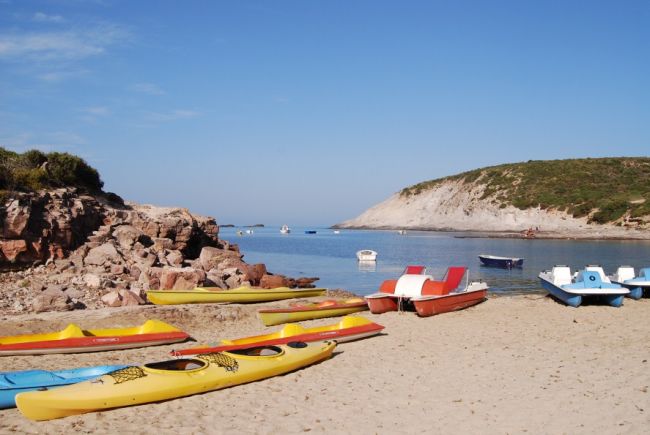Kayak e pedalò colorati su una spiaggia sabbiosa.