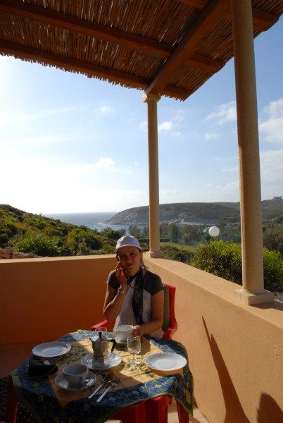 Persona seduta a un tavolo apparecchiato su una terrazza con vista mare.