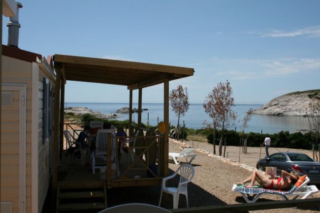 Una persona prende il sole su una sdraio accanto a un patio vicino al mare.