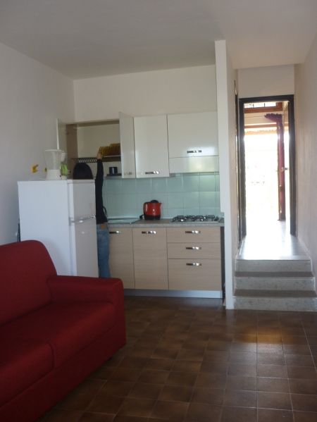 Una cucina moderna con frigorifero, piano cottura e un divano rosso.