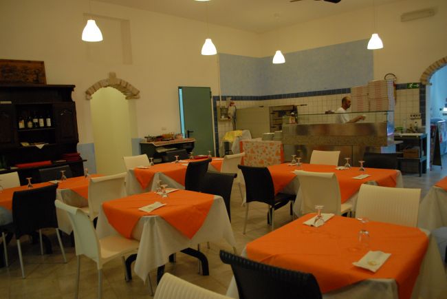 Un ristorante con tavoli apparecchiati e tovaglie arancioni.