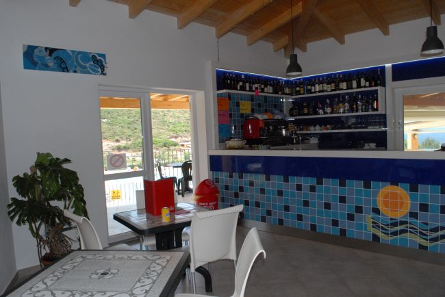 Un bar con tavoli e sedie bianche, decorato con piastrelle blu.