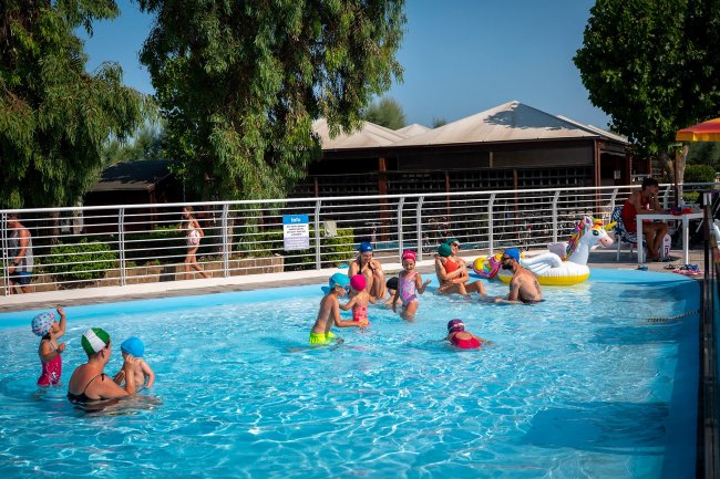 Bambini e adulti giocano in piscina.