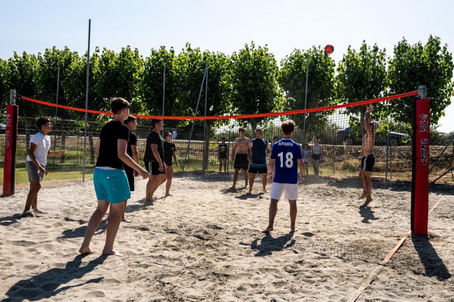 Partita di beach volley con diversi giocatori.