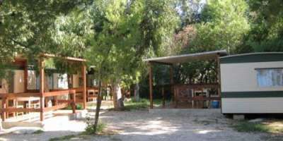 Piazzola con roulotte e bungalow in un'area alberata.