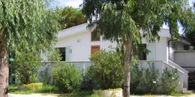 Casa bianca circondata da alberi e cespugli verdi.