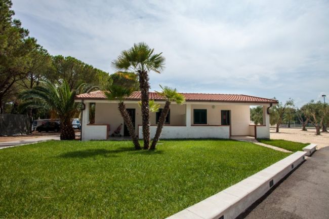 Casa bianca con tetto rosso e giardino verde.