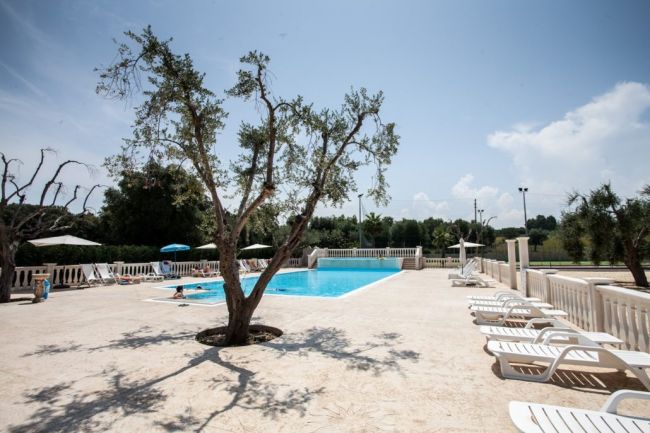 Una piscina con lettini e ombrelloni.