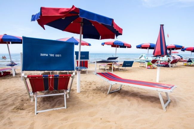 Lettini e ombrelloni blu e rossi sulla spiaggia.