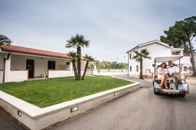 Marciapiede in giardino con golf cart e case bianche.