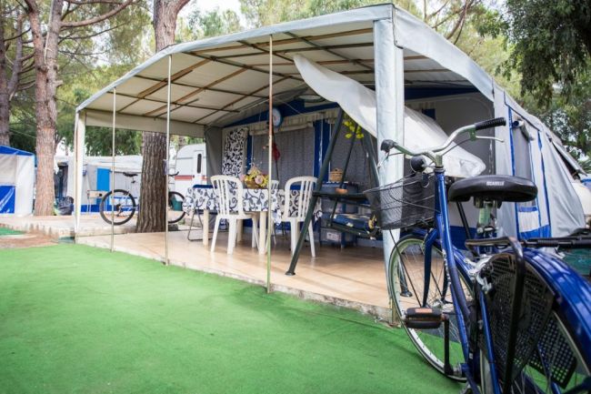Tenda da campeggio con tavolo e sedie, bici davanti.