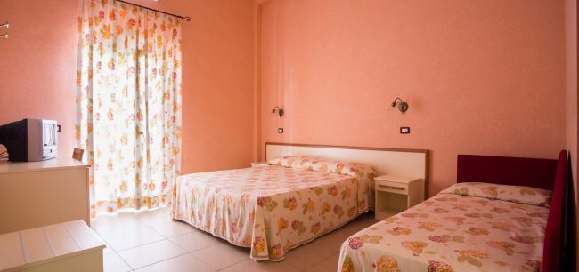 Camera con due letti e pareti rosa.