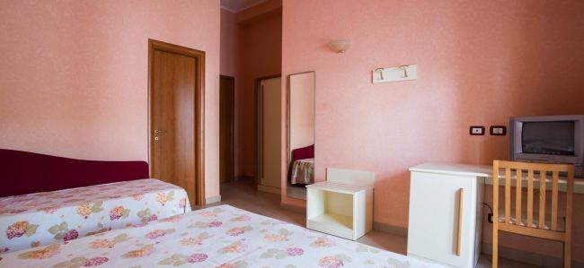 Camera rosa con TV e armadio a specchio.