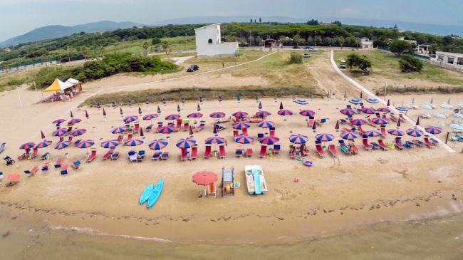 Spiaggia con ombrelloni colorati e pedalò sulla sabbia.