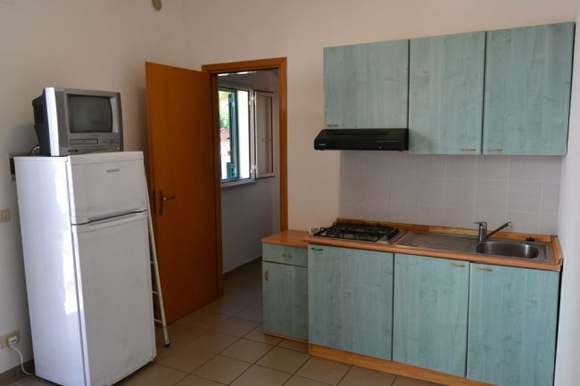 Cucina semplice con frigo, fornelli e armadietti verdi.