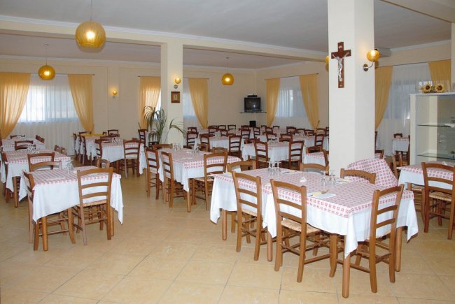 Sala da pranzo con tavoli apparecchiati e sedie.