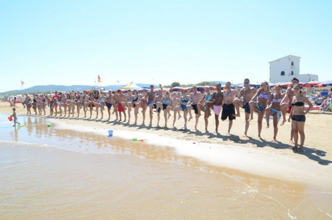 Persone in costume posano in fila sulla spiaggia.