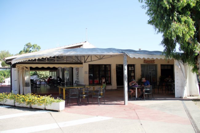 Ristorante con tettoia e tavoli all'aperto, piante intorno.