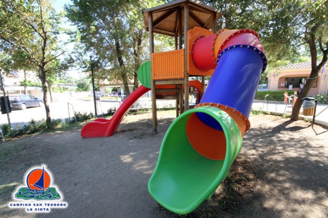 Un parco giochi con scivoli colorati sotto gli alberi.