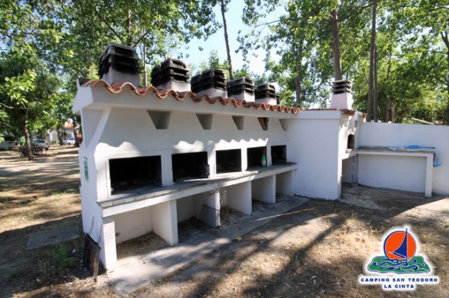 Barbecue in muratura in un'area verde.
