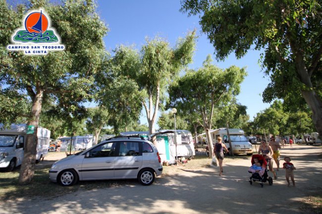 Un campeggio con auto parcheggiate e persone che camminano.