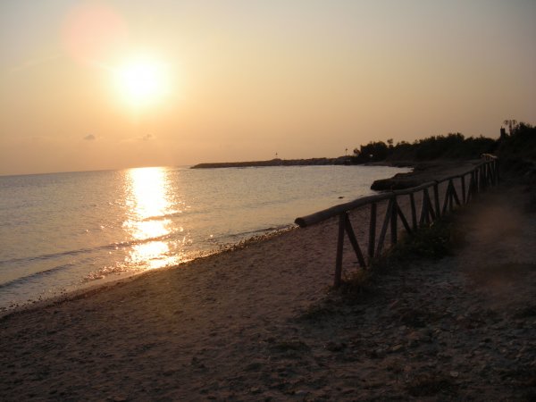 Spiaggia al tramonto con ringhiera di legno.