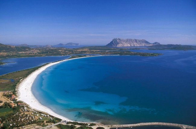 Spiaggia con sabbia bianca e mare azzurro.