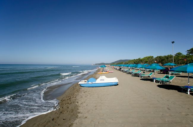 Spiaggia con lettini e ombrelloni blu.
